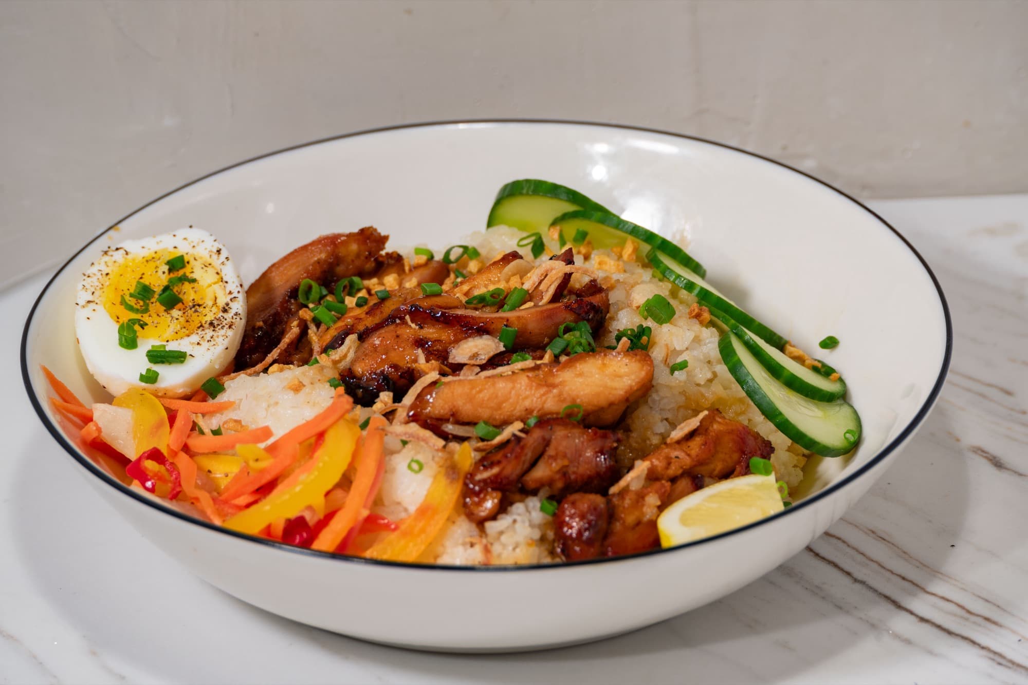 An inasal rice bowl with jammy egg, cucumbers, and pickled atchara