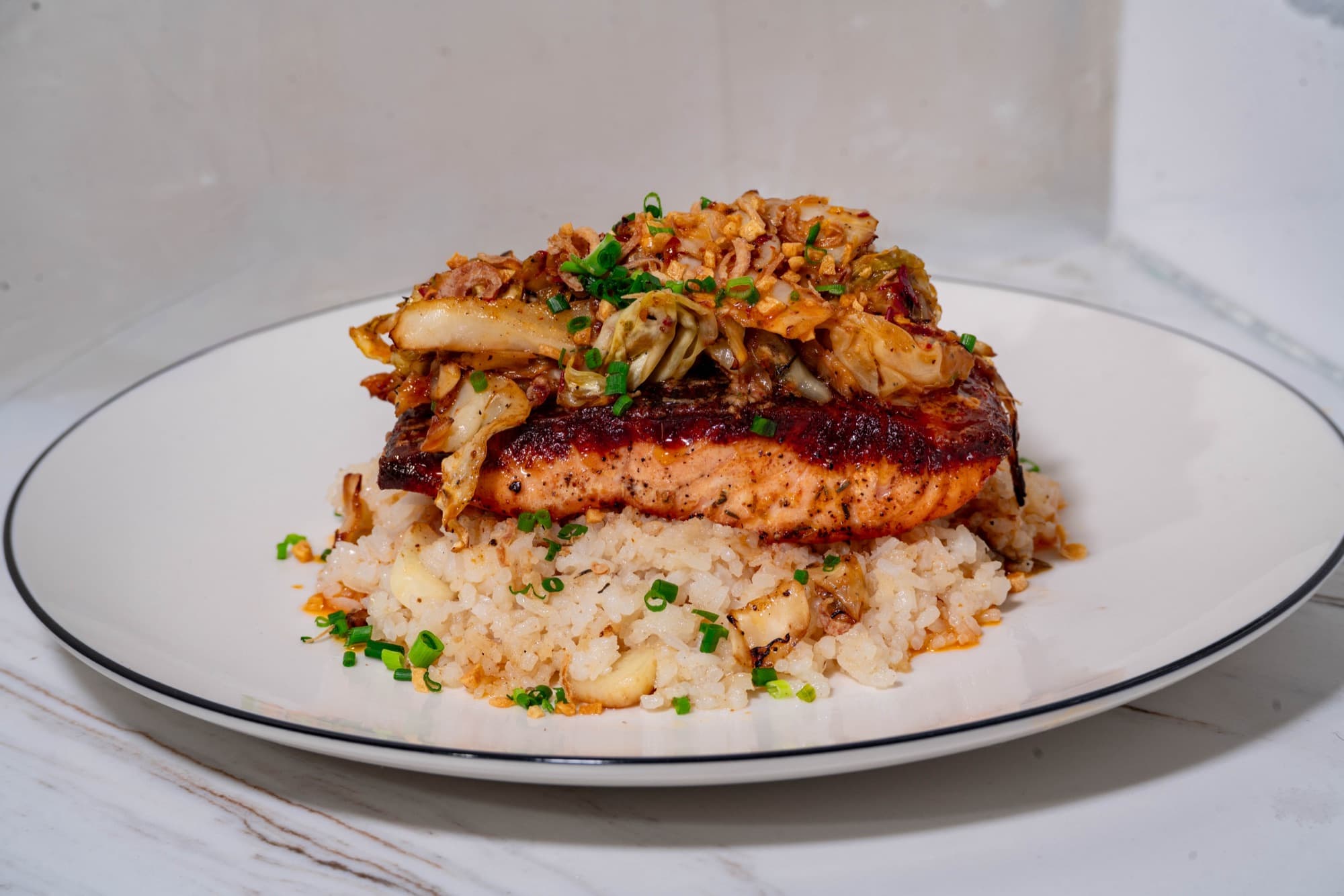 Blackened salmon over garlic rice, crowned with charred cabbage