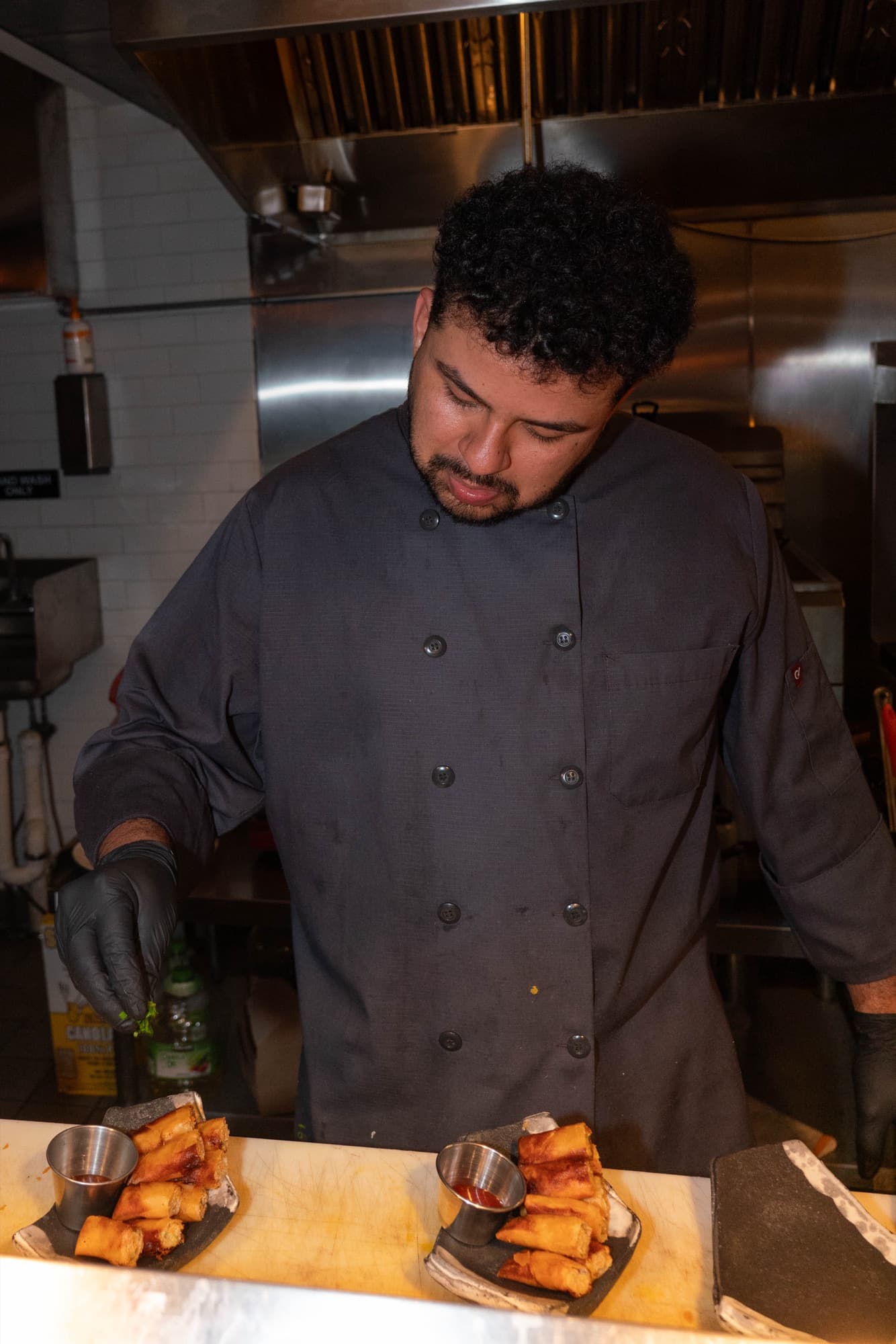 A chef plating lumpia at the kitchen pass