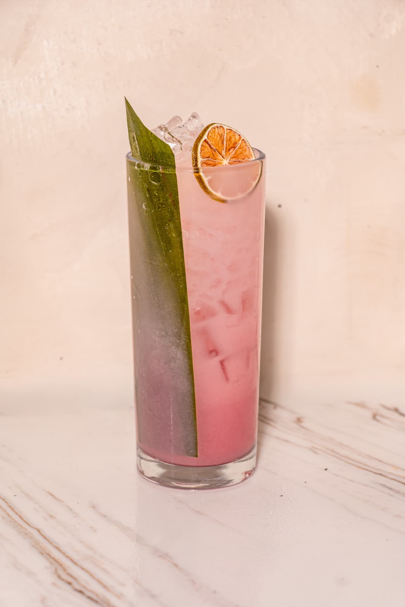 The Rice Rice Baby, a blush-pink highball with a pandan leaf and dehydrated calamansi