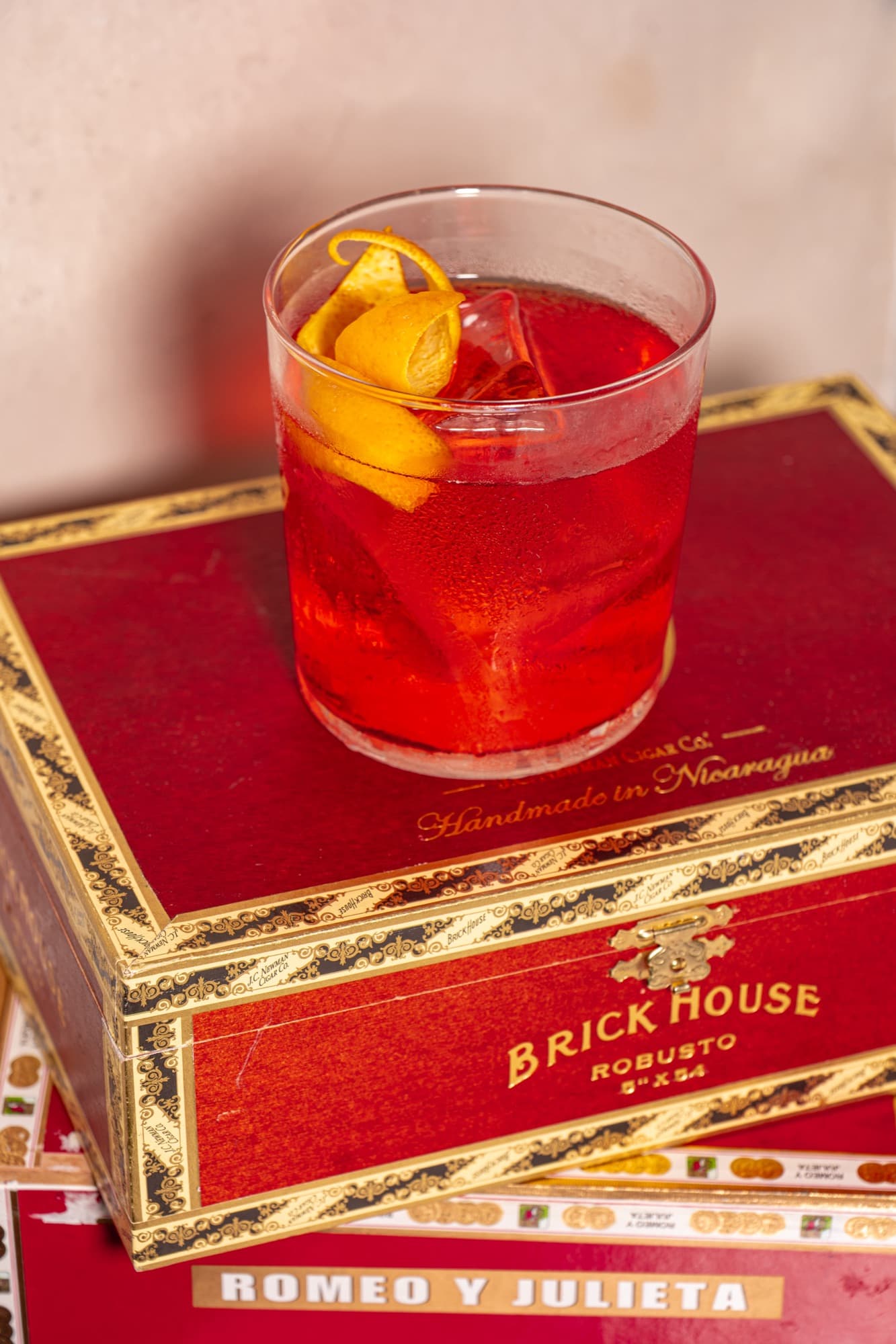 The Bananigans, a scarlet rocks pour with an orange twist, perched on a cigar box