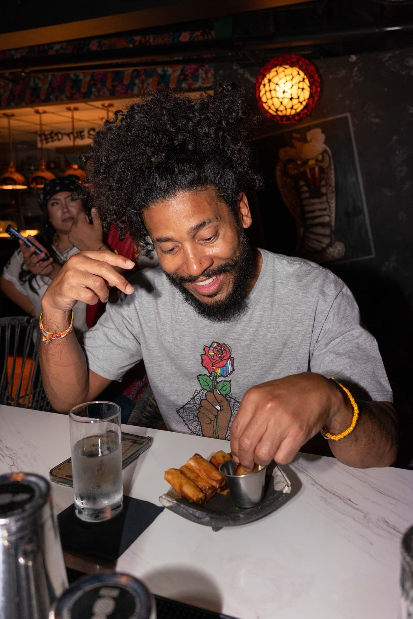 A guest grinning while dipping a lumpia at the bar